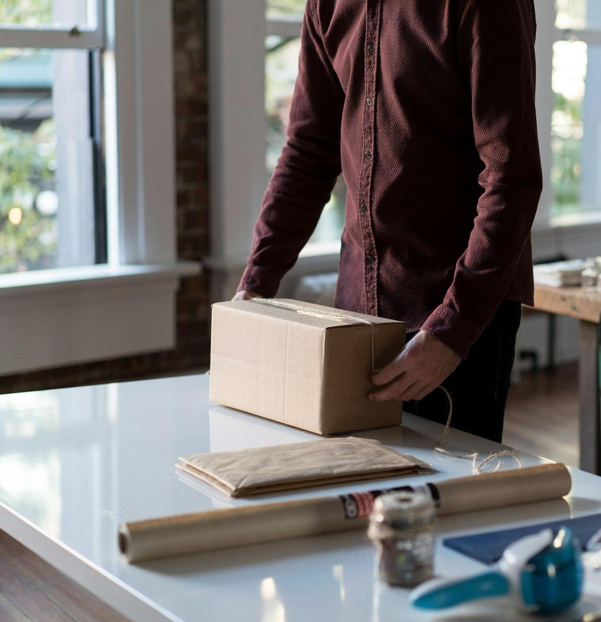 person holding cardboard box on table